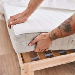 Uomo solleva l'angolo del materasso per mettere il topper letto